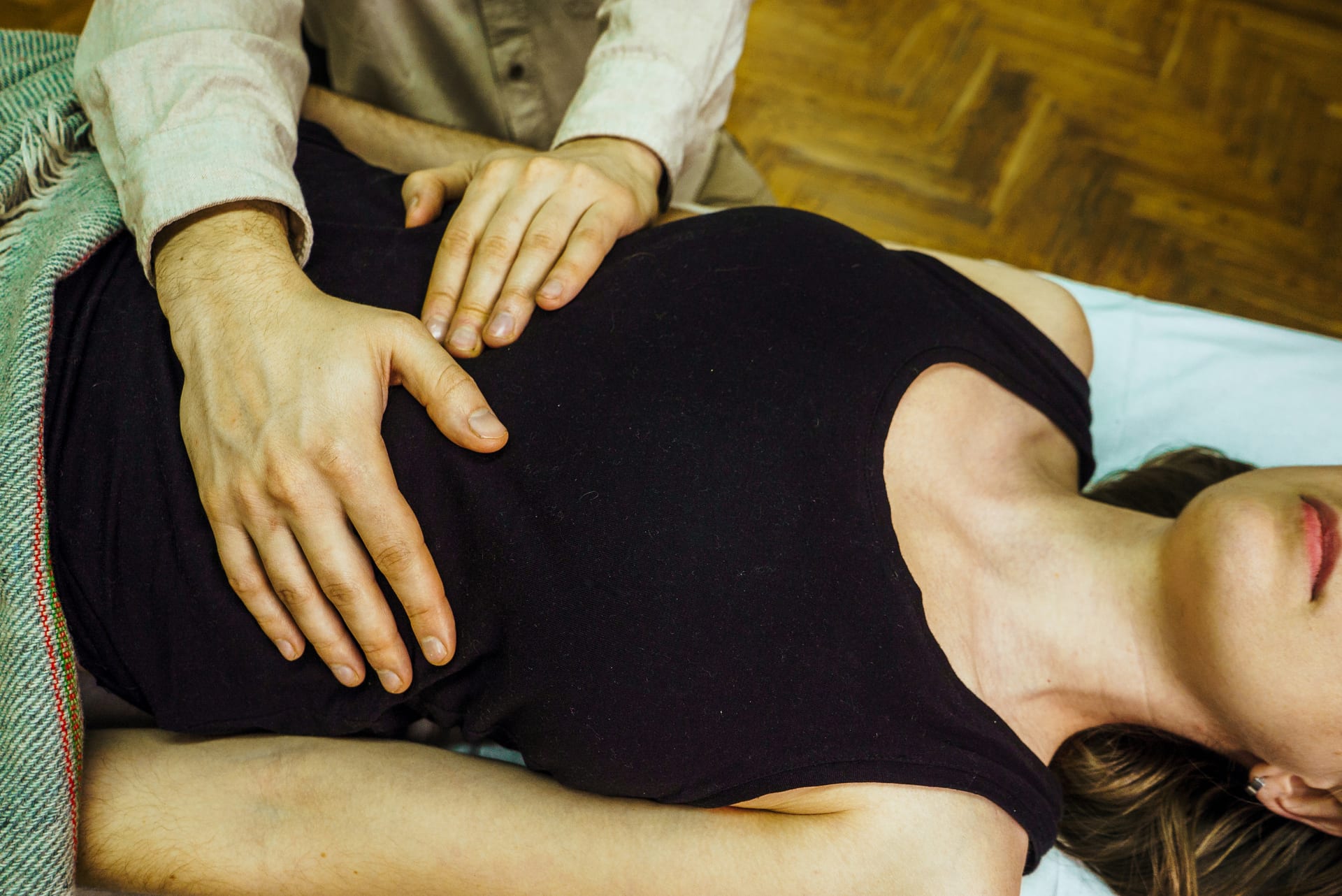 Practitioner's hands gently working on a client's abdomen during visceral manipulation
